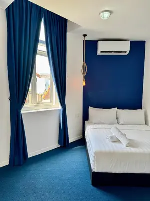 a blue room with a bed and a window at The Harbour by Moonknight in George Town
