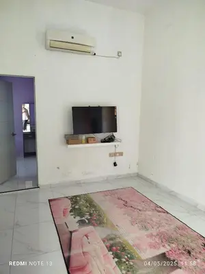 a living room with a television and a rug on the floor at Homestay Usrati in Taiping