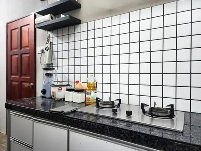 a kitchen with white tiled walls and a counter top at Dirgahayu Homestay II Nuri in Kulim