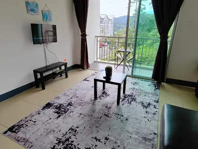 a living room with a table and a large window at Golden hill somersqaure 3 bed room islam apartment in Tanah Rata