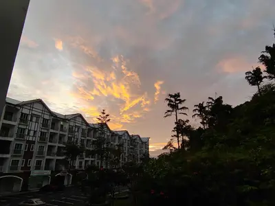 a sunset over a city with buildings and palm trees at Golden hill somersqaure 3 bed room islam apartment in Tanah Rata
