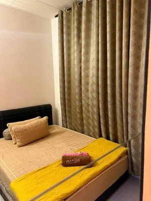 a bed with a yellow blanket and a curtain at JJ Homestay Taman Manggis in Balik Pulau
