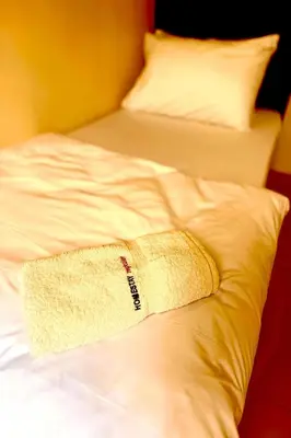 a towel is sitting on a white bed at Homestay MyKulim in Kulim