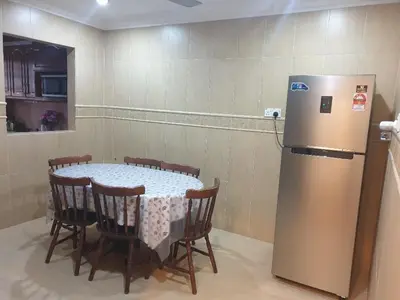 a table with chairs and a refrigerator in a room at Kinrara HomeStay right at the Heart of Puchong in Gua Sai
