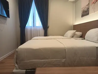 a bedroom with two beds and a window at Karasky Hotel in Simpang Ampat