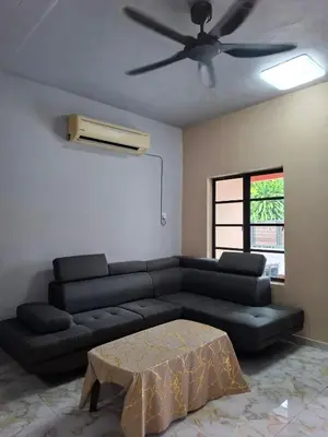 a living room with a black couch and a ceiling fan at Family Homestay Bidor in Gua Sai