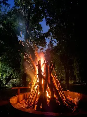a fire pit with people standing around it at night at Ulu River Lodge, Riverbug Perak in Gopeng