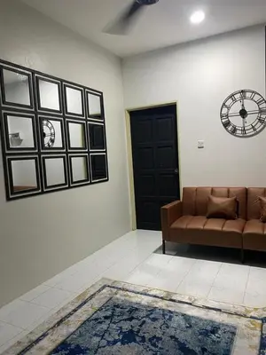 a living room with a couch and a clock on the wall at AISY Homestay MERAPOH in Pulai