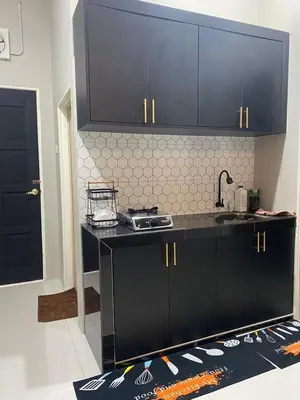 a kitchen with black cabinets and a counter top at AISY Homestay MERAPOH in Pulai