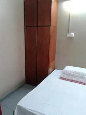 a bedroom with a bed and a wooden cabinet at HotelMalaya in Taiping