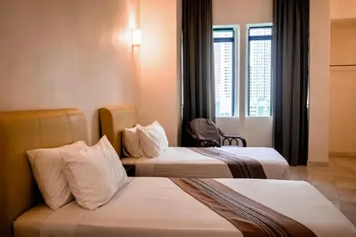 a hotel room with three beds and a window at Stallions Suite in Jelutong