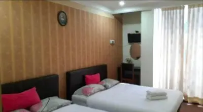 a bedroom with two beds and a clock on the wall at Hotel Tropicanna Pulai Point in Ipoh