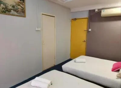 a room with two beds and a yellow door at Hotel Tropicanna Pulai Point in Ipoh