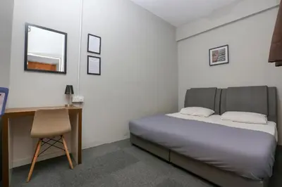 a bedroom with a bed and a desk and a chair at SPOT ON 89751 Bed Station Guest House in Tanah Rata