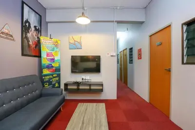 a living room with a couch and a tv on a wall at SPOT ON 89751 Bed Station Guest House in Tanah Rata