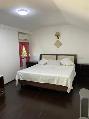 a bedroom with a bed with white sheets and a window at Nipah Bay Villa in Pangkor