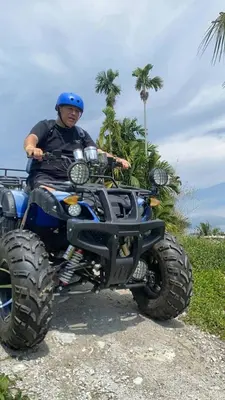 a man in a blue helmet sitting on a atv at Quadruple Traditional Wooden GuestHouse in Balik Pulau