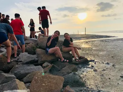 a group of people sitting on rocks on the beach at Junior Suite Nature of Penang Guesthouse in Balik Pulau