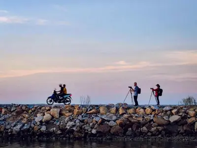 a group of people standing on a rock wall with a motorcycle at Tatami Room Malay Wooden Stay in Balik Pulau