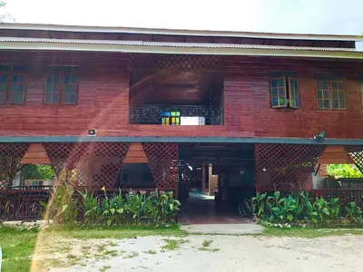 a red brick building with a balcony and plants at Tatami Room Malay Wooden Stay in Balik Pulau