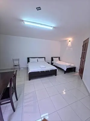 a room with two beds and a table in it at Zahaar KN Inn in Batu Ferringhi