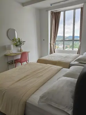 two beds in a room with a desk and a window at Almira Homestay in Brinchang