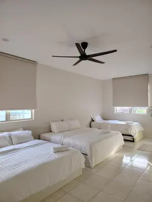 a bedroom with two beds and a ceiling fan at Relax Guest House Bakap Indah in Kampong Gurun