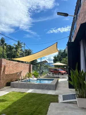 a swimming pool in a yard with a yellow awning at Kurie Redbrick House in Balik Pulau