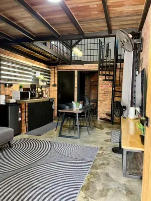 a living room with a table and a kitchen at Kurie Redbrick House in Balik Pulau