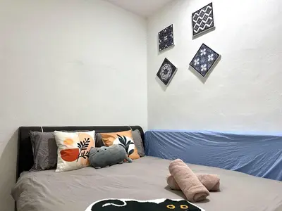 a bedroom with a bed with pillows and pictures on the wall at Specious Living Cozy House in Bukit Mertajam