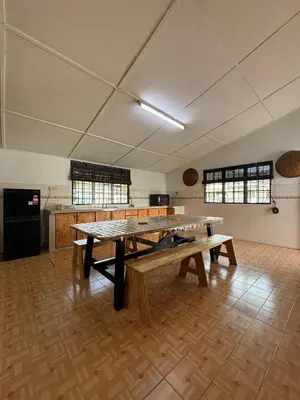 a large room with wooden tables and a kitchen at Rumah Bonda in Gua Sai
