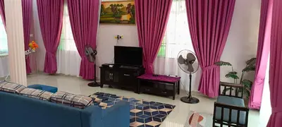 a living room with pink curtains and a blue couch at ASTANA INN HOMESTAY Balik Pulau in Balik Pulau
