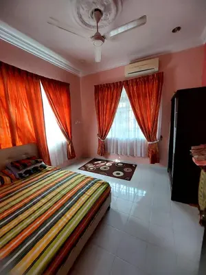 a bedroom with a large bed with orange curtains at ASTANA INN HOMESTAY Balik Pulau in Balik Pulau
