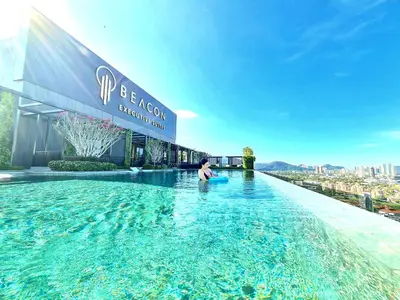 a man sitting on the edge of a swimming pool on a building at Beacon Executive Suite Penang George Town in George Town