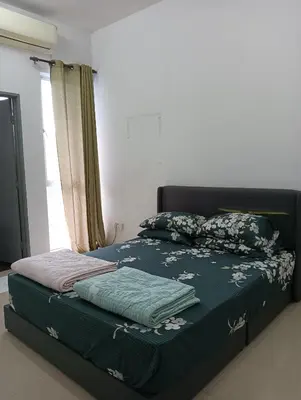 a bedroom with a bed with green sheets and a window at Taman yu sungai besar in Sungai Besar