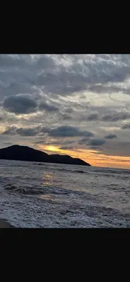 a view of the ocean with the sunset in the background at By The Sea in Batu Ferringhi