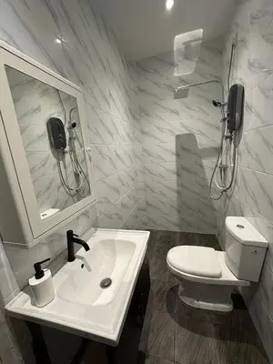 a white bathroom with a toilet and a sink at Ahnaf Guesthouse in Sitiawan
