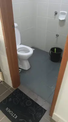 a bathroom with a toilet and a black rug at Homestay kita in Gua Sai