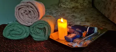 a candle and towels on a table next to a bed at Ruma Inn Homestay Perlis in Gua Sai