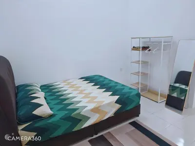 a bedroom with a bed with a green comforter at ZARI Homestay Kamunting in Gua Sai