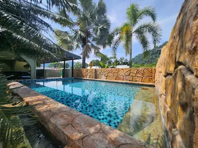 a swimming pool with a stone wall and palm trees at Ipoh Tambun pool villa 5br 18pax bbq mahjong in Tambun