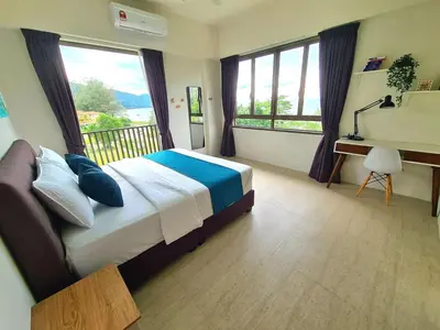 a bedroom with a bed and a desk and windows at By The Sea - Beachfront Bliss at Batu Ferringhi in Batu Ferringhi