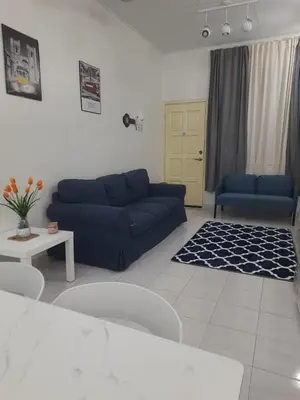 a living room with a blue couch and a table at Cozy AiZHome in Balik Pulau
