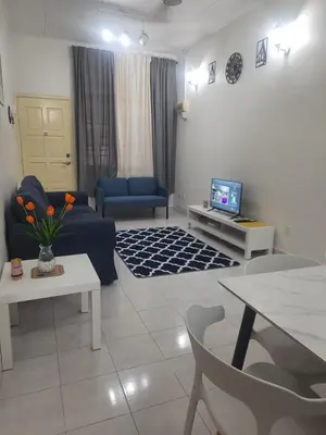 a living room with a blue couch and a tv at Cozy AiZHome in Balik Pulau