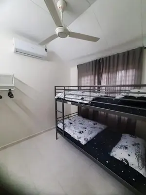 a room with two bunk beds and a ceiling fan at Cozy AiZHome in Balik Pulau