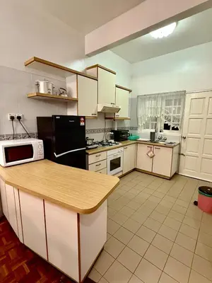 a kitchen with white cabinets and a black refrigerator at A Highland Retreat in Tanah Rata in Tanah Rata