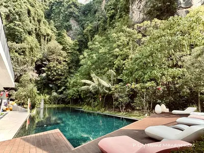 a swimming pool with lounge chairs in front of a mountain at The Cove Hillside Residence Ipoh by PLY Home in Ipoh