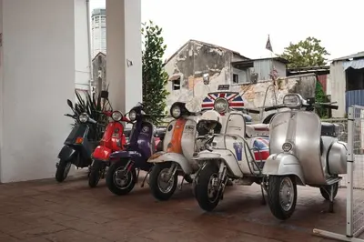 a group of motorcycles and scooters parked next to a building at C Y C Heritage Hotel in George Town