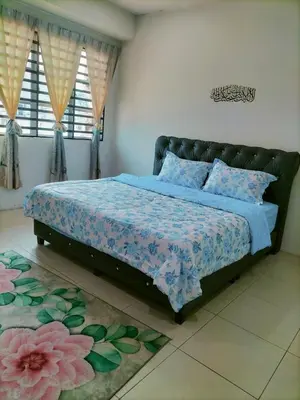 a bedroom with a bed with a blue comforter at Homestay Ustaz in Batu Gajah