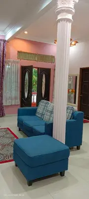 a living room with two blue couches and a column at A I HOMESTAY Balik Pulau in Balik Pulau